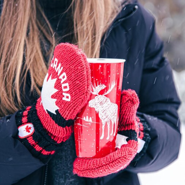 eine Frau mit roten Handschuhen hält einen roten Becher mit dem Wort Liebe drauf