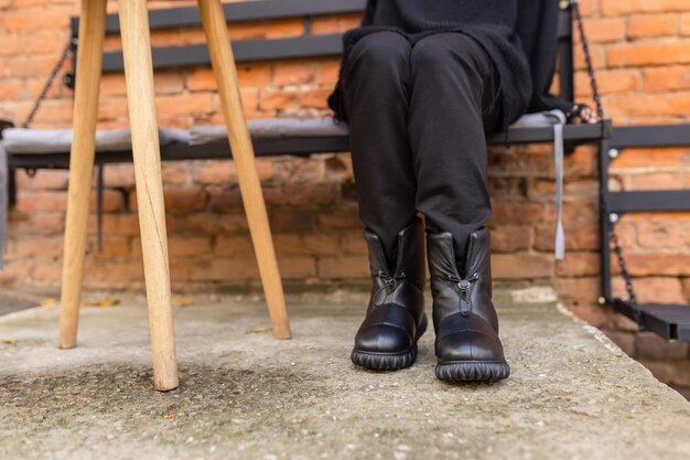 Eine Frau mit schwarzen Lederstiefeln sitzt auf einer Bank.