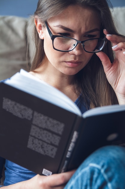 Eine Frau mit Sehproblemen liest ein Buch mit Brille