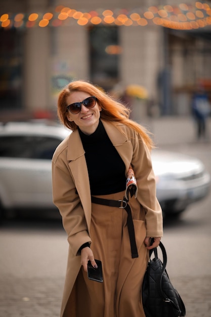 Eine Frau mit Sonnenbrille geht die Straße entlang. Spaziergang in der Herbststadt