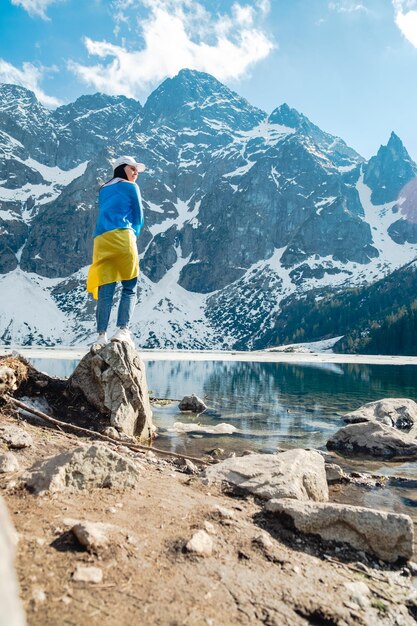 Eine Frau mit ukrainischer Flagge steht am Ufer eines Sees Morskie Oko