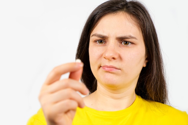 Eine Frau mit verärgertem Gesicht hält eine Pille in der Hand