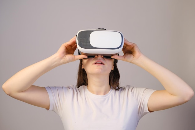 Eine Frau mit Virtual-Reality-Brille blickt vor einem grauen Hintergrund auf