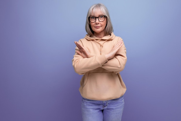 Eine Frau mittleren Alters mit grauen Haaren zeigt auf Studiohintergrund mit Kopierraum eine Geste, die nicht zutrifft