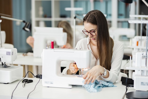 Eine Frau näht mit der elektrischen Nähmaschine Modeschneiderwerkstatt