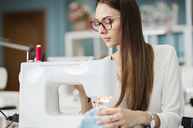 Eine Frau näht mit der elektrischen Nähmaschine Modeschneiderwerkstatt