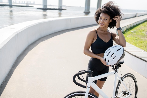 Eine Frau nutzt einen Fahrrad-Öko-Transport im Stadt-Fitness-Cardio-Training hält einen Helm