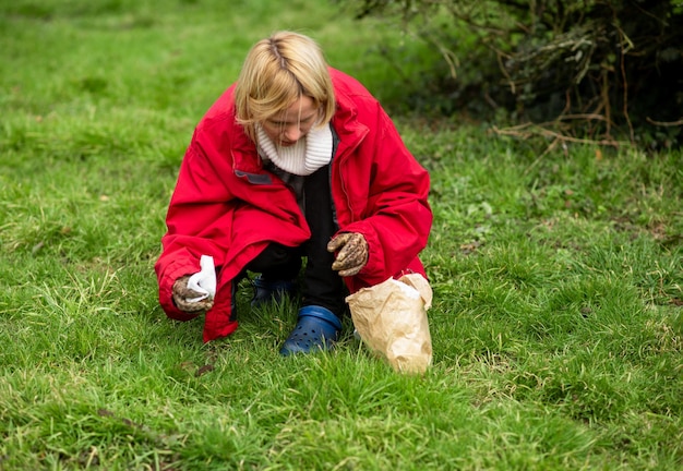 Eine Frau räumt Hundehaufen auf dem Rasen im Hof des Hauses auf Gebietsreinigung