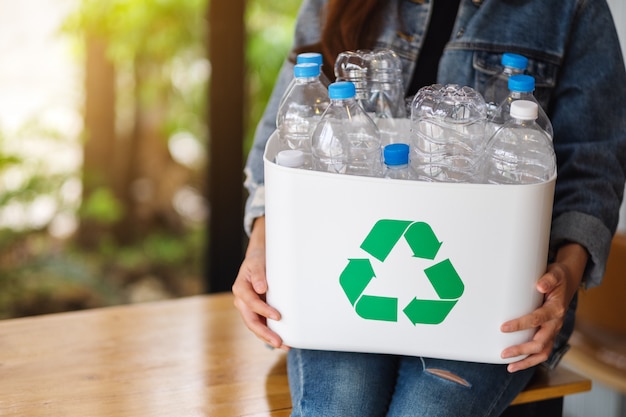 Eine Frau sammelt und hält eine recycelbare Müllplastikflasche in einem Mülleimer zu Hause