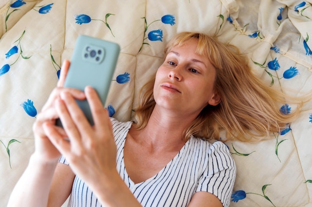 Eine Frau schaut auf das Telefon auf dem Bett im Zimmer