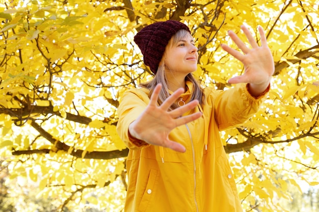 Eine Frau schließt ihre Hände vor dem Hintergrund der gelben Herbstblätter