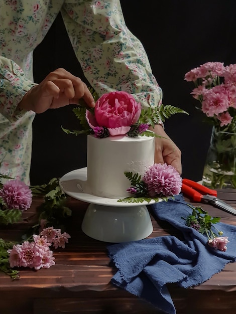 Eine Frau schneidet einen Kuchen mit einer Blume darauf an.