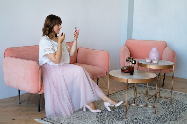 Foto eine frau sitzt auf dem sofa im zimmer und malt sich die lippen