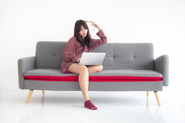 Eine Frau sitzt auf einem Sofa und schaut sich einen Job auf einem Laptop an