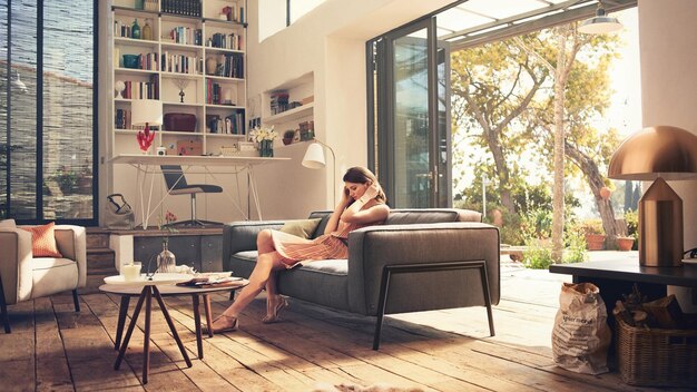 Foto eine frau sitzt auf einer couch und schaut auf ihr handy