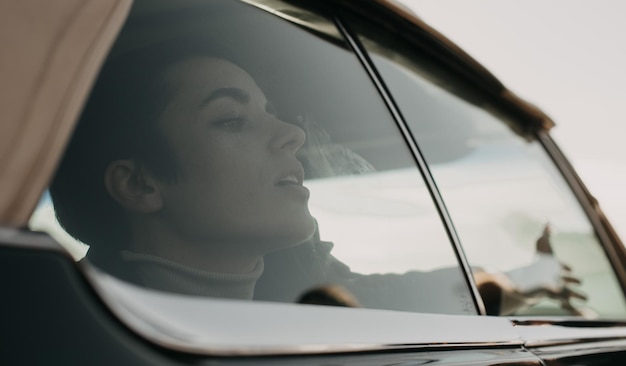 Eine Frau sitzt in einem Auto, ihr Gesicht spiegelt sich im Fenster.