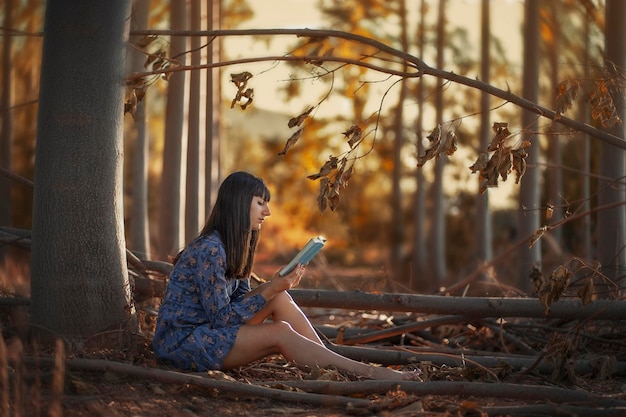 Eine Frau sitzt in einem Wald und liest ein Buch.