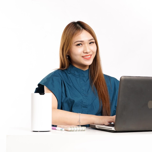 Eine Frau sitzt mit einem Laptop und einem Stift an einem Tisch.