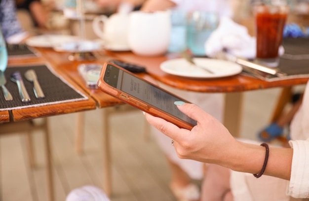 Foto eine frau sitzt mit einem tablet in der hand an einem tisch.