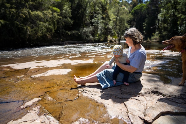 Eine Frau sitzt mit ihrem Baby auf einem Felsen in einem Fluss