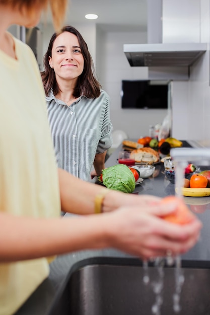 Eine Frau spricht mit einem Freund, der Gemüse im Küchenbecken wäscht