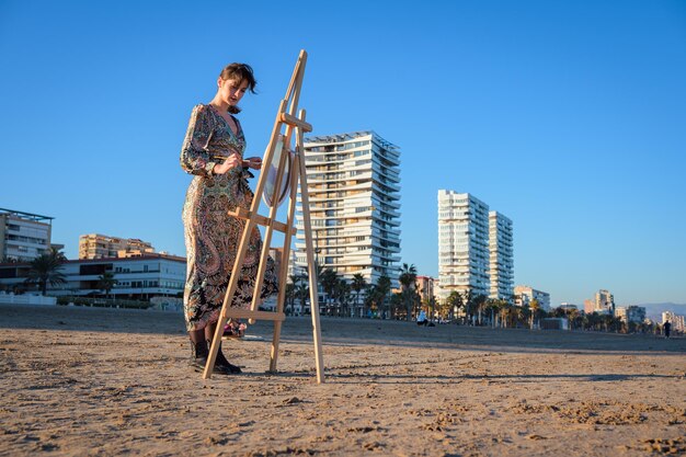 Eine Frau steht am Strand neben einem Esel