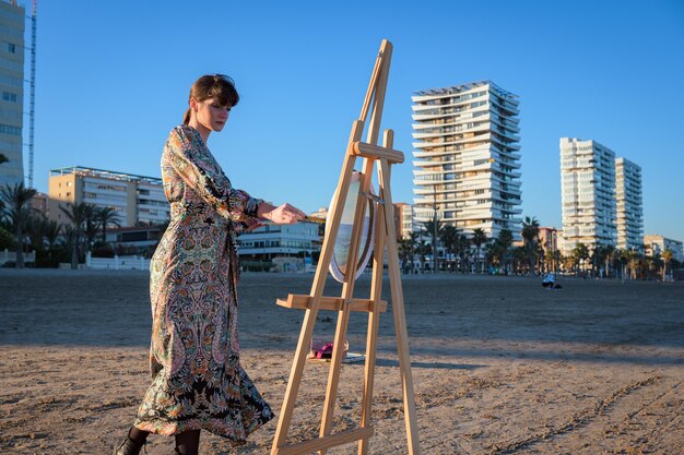 Eine Frau steht am Strand neben einem Esel