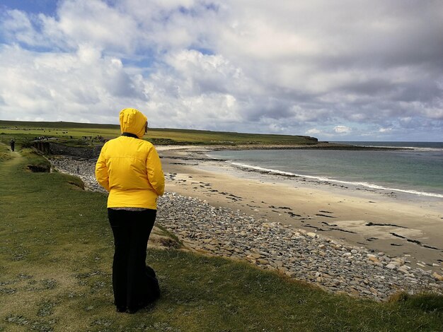 Eine Frau steht am Strand vor einem bewölkten Himmel