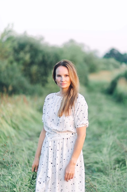 Eine Frau steht auf einem Feld vor einem Baum