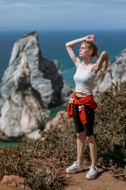 Eine Frau steht auf einem Felsen am Meer.