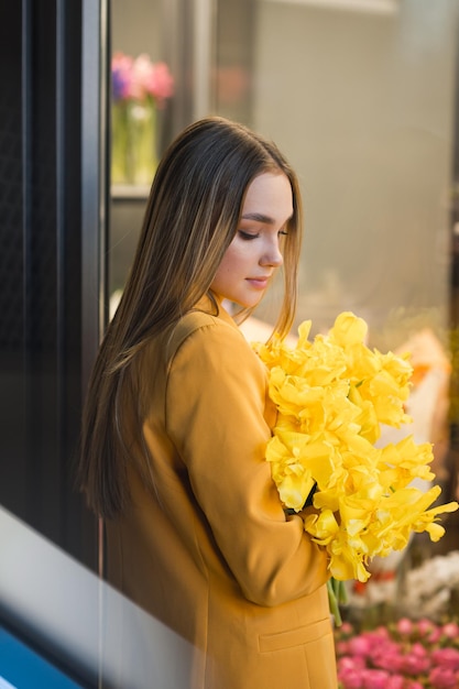 Foto eine frau steht im freien, trägt ein gelbes outfit und hält blumen