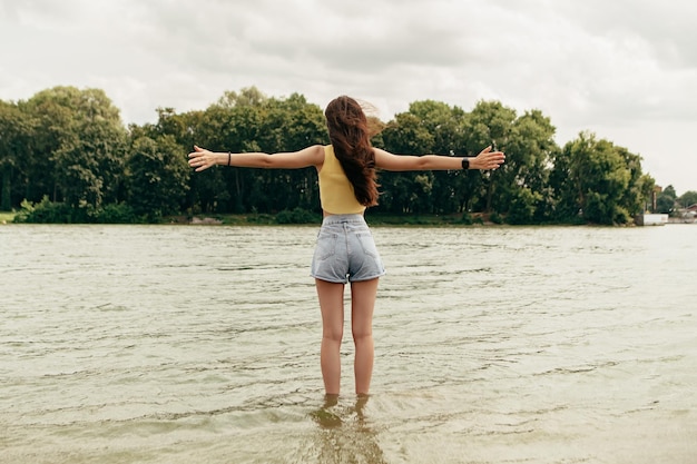 Eine Frau steht mit ausgestreckten Armen im Wasser