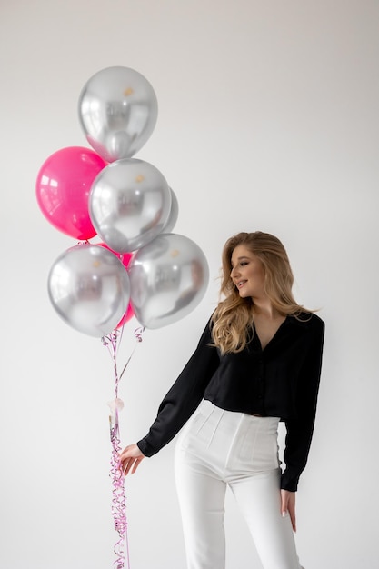 Eine Frau steht neben einem rosa und silbernen Ballon mit dem Wort Liebe darauf.