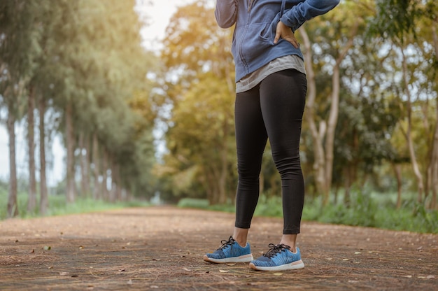 Eine Frau steht, um nach dem Joggen natürliche Luft einzuatmen. Naturpark. Gesundes und Lifestyle-Konzept.