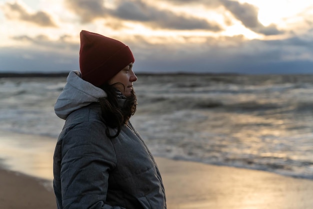 eine Frau steht während eines Sturms in der Kälte am Meeresrand