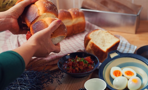 Eine Frau stellt Brot mit einer Schüssel Eier auf einen Tisch.