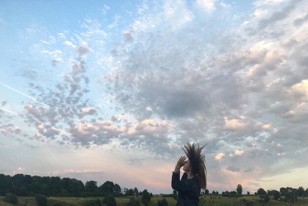 Eine Frau tanzt bei Sonnenuntergang gegen den Himmel