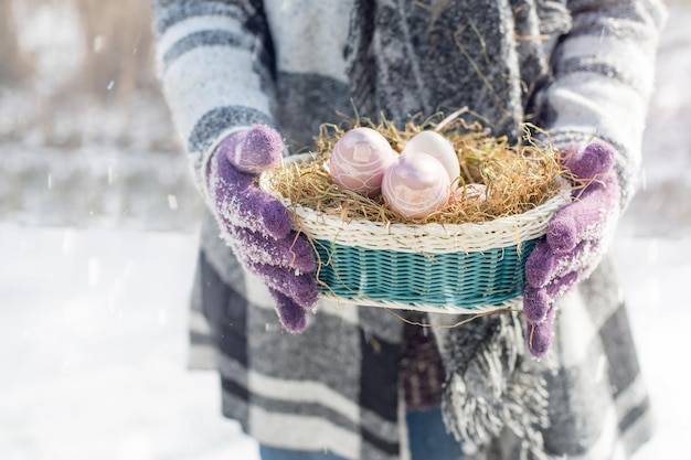 Eine Frau trägt ein Osternest im Schnee