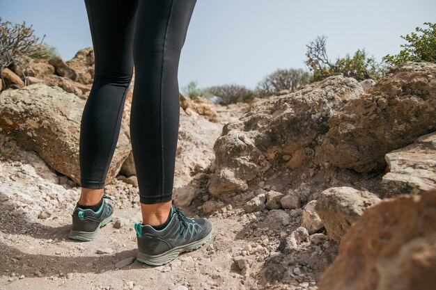 Foto eine frau trägt schwarze hosen und schuhe und steht auf einem felsigen pfad in der nähe ihrer füße