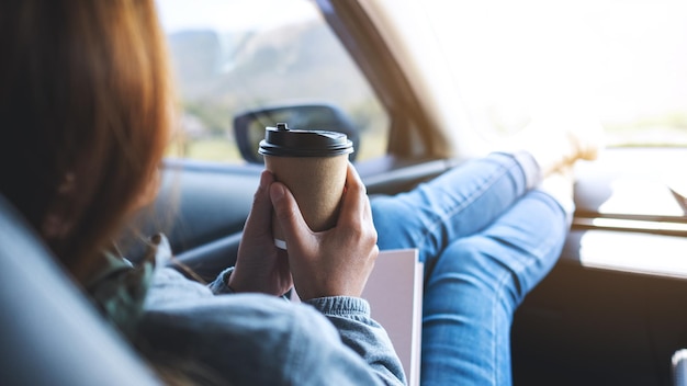 Eine Frau trinkt Kaffee, während sie mit dem Auto fährt