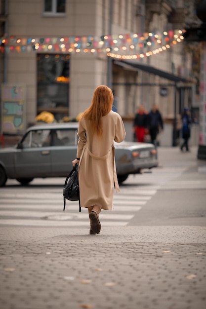 Eine Frau überquert an einem Fußgängerüberweg die Straße. Frau in der Stadt