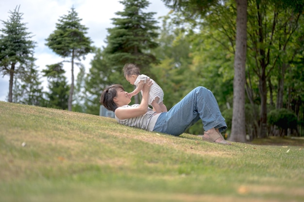 Eine Frau und ein Baby liegen auf dem Gras und das Gras schaut in die Kamera.