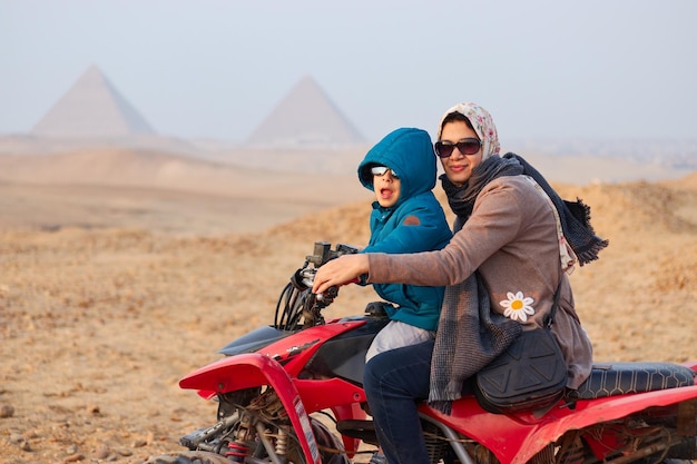 Eine Frau und ein Junge fahren Quad vor den Pyramiden von Gizeh.