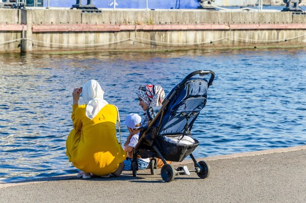 Eine Frau und ein Kind sitzen am Ufer und schauen aufs Wasser.