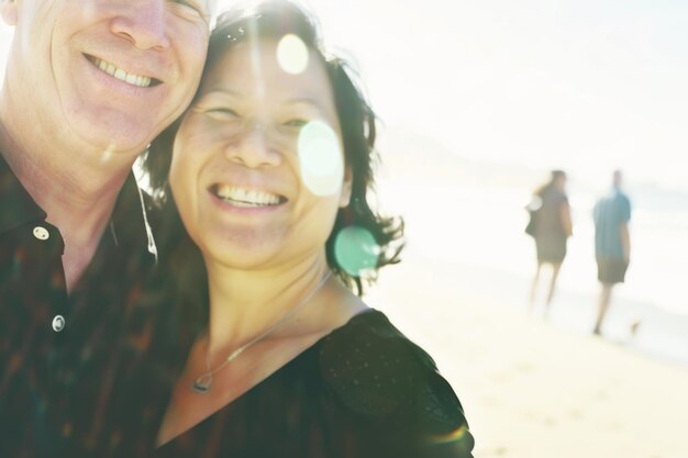 Eine Frau und ein Mann stehen auf einem Sandstrand und blicken mit Lächeln auf den Horizont