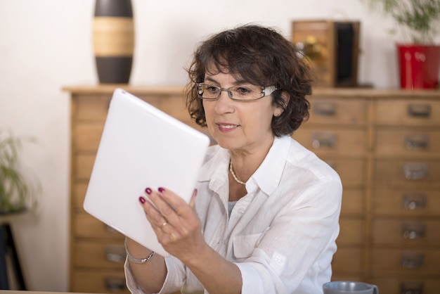 Eine Frau von mittlerem Alter, die eine Computertablette verwendet