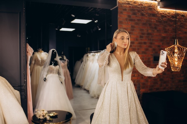 Foto eine frau wählt ein hochzeitskleid in einem ausstellungsraum, eine zukünftige braut kauft ein hochzeitskleid in einem geschäft