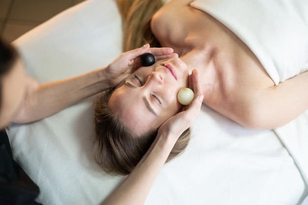 Eine Frau wird mit einem schwarzen Ball auf dem Kopf massiert.