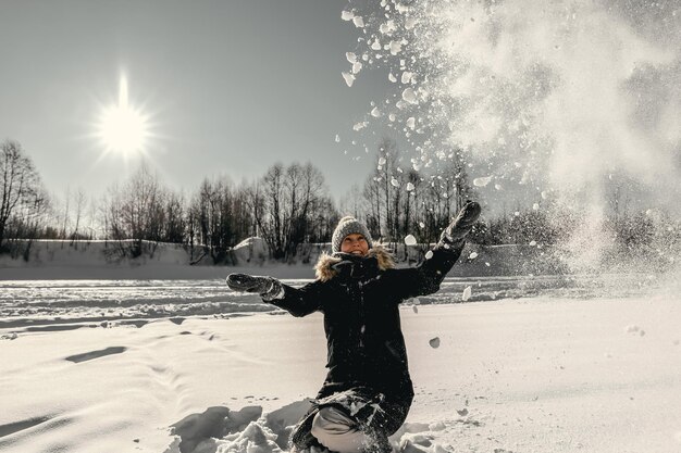 Eine Frau wirft gegen die Sonne Schnee in die Luft