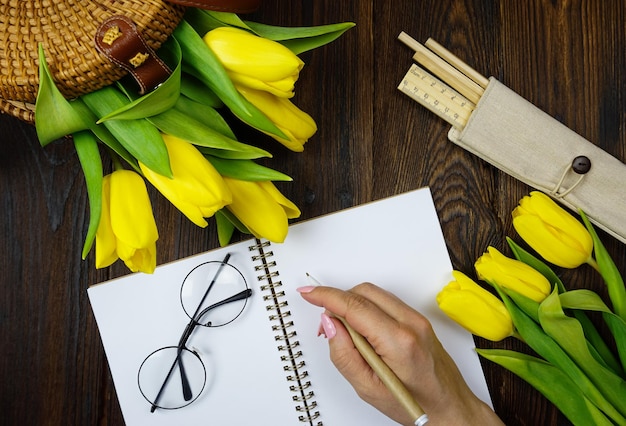 Eine Frau zeichnet Blumen mit Brille auf einem Tisch